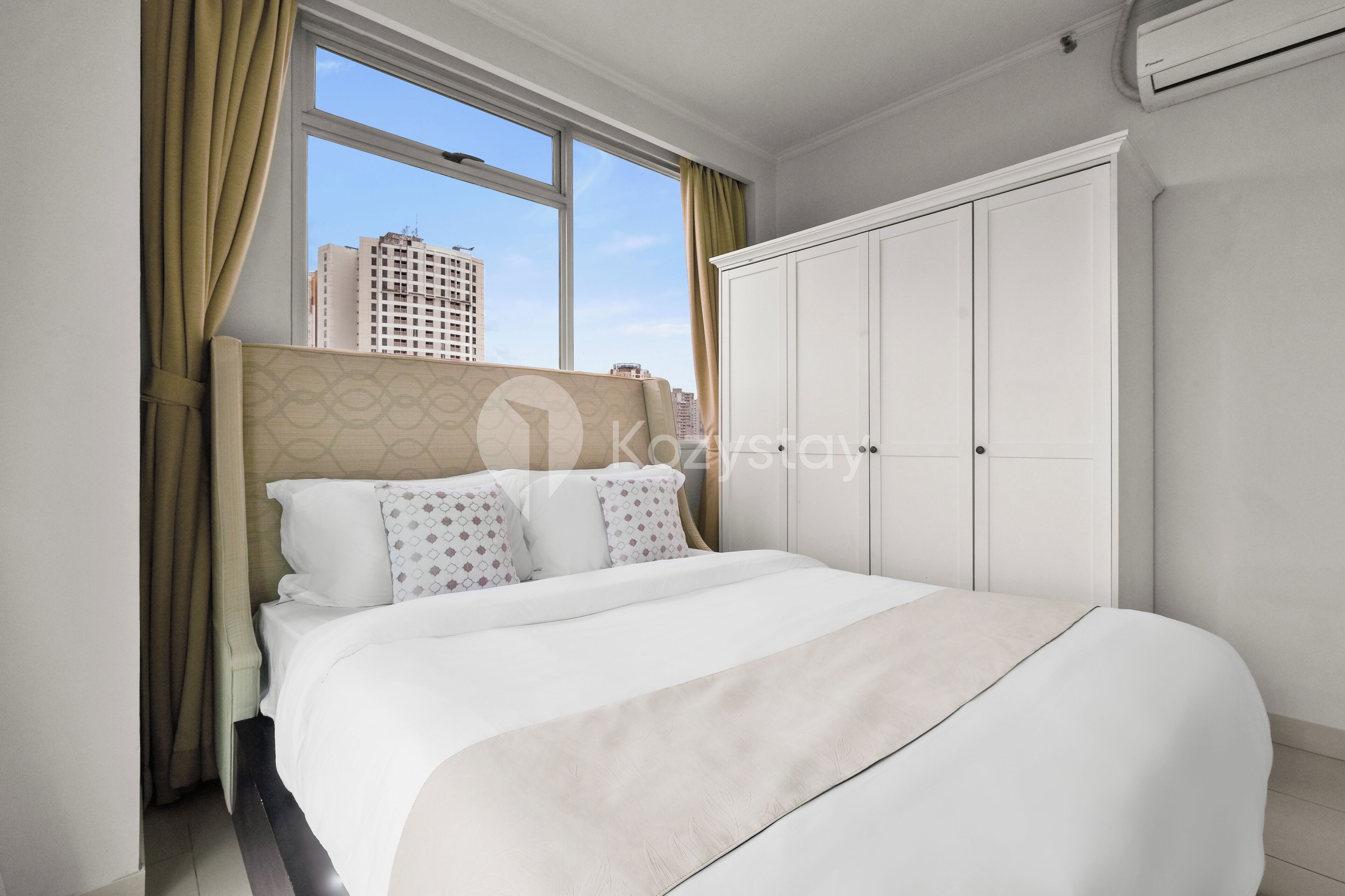 Een hotelkamer met een groot bed, een garderobe en een raam met gordijnen.