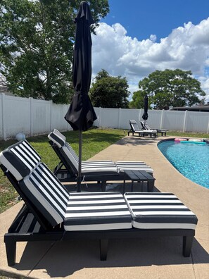 A poolside area with lounge chairs and an umbrella.