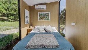 Un dormitorio con una cama grande, una ventana, aire acondicionado instalado en la pared y un cartel en la pared.