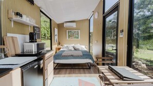 Una habitación moderna con cama, escritorio, cafetera y vistas al exterior.