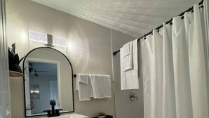Ein Badezimmer mit Toilette, Waschbecken mit Spiegel und Duschvorhang.