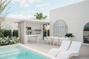A modern outdoor pool area with a kitchen and dining space. - Mira Maya Villa Nakornnayok (Nakhon Nayok)