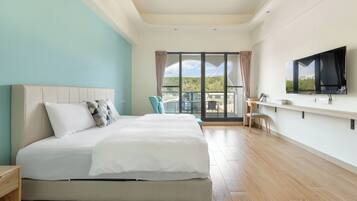 Una habitación de hotel moderna con una cama grande, un televisor, un balcón con vistas y un escritorio con una silla.