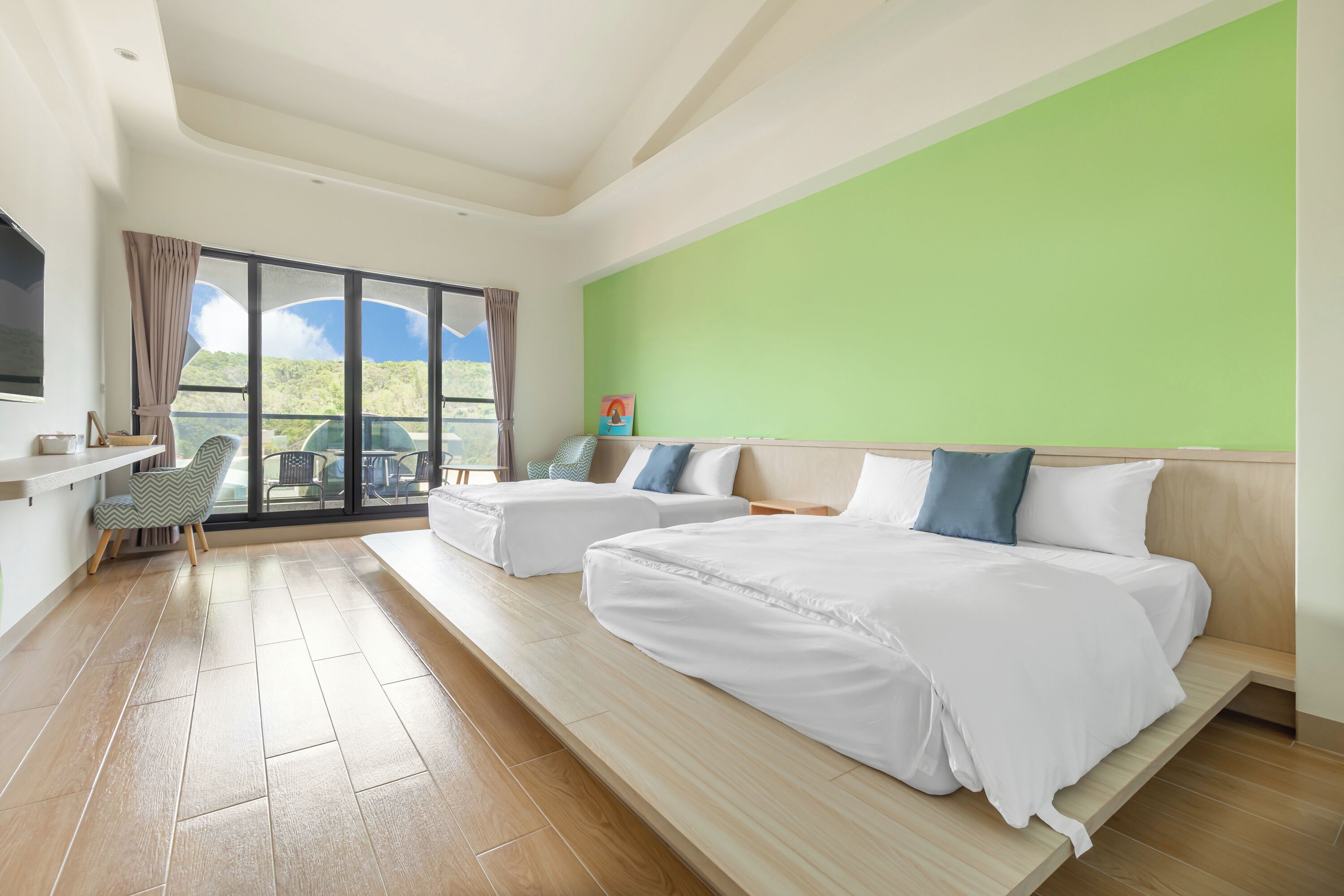 Habitación de hotel con dos camas, un escritorio y vistas al exterior.