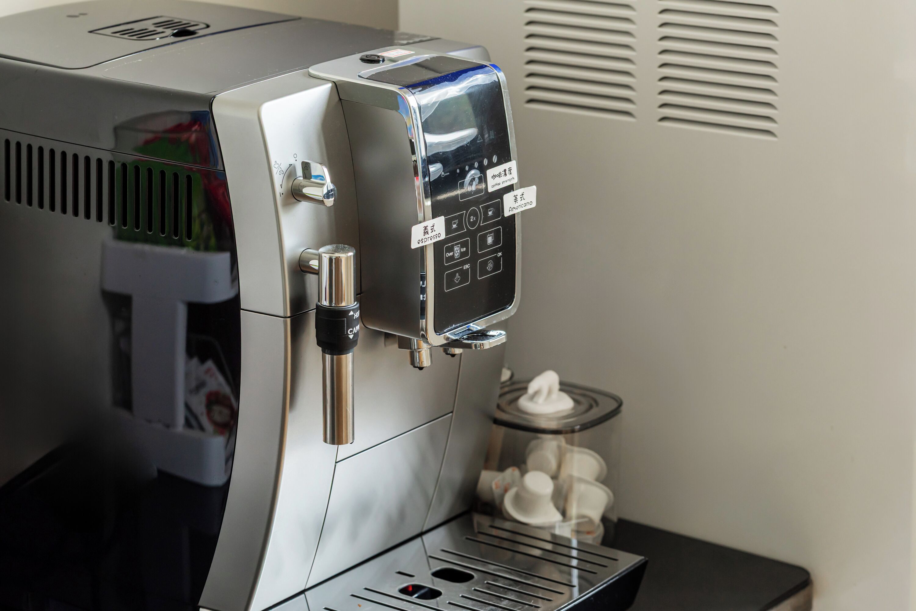 A coffee machine with a digital interface and a milk frothing station.