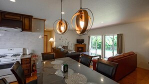 A modern kitchen with a dining area, featuring a large table with placemats, a gas stove, and a coffee machine. - Lulu Manza (Onna)