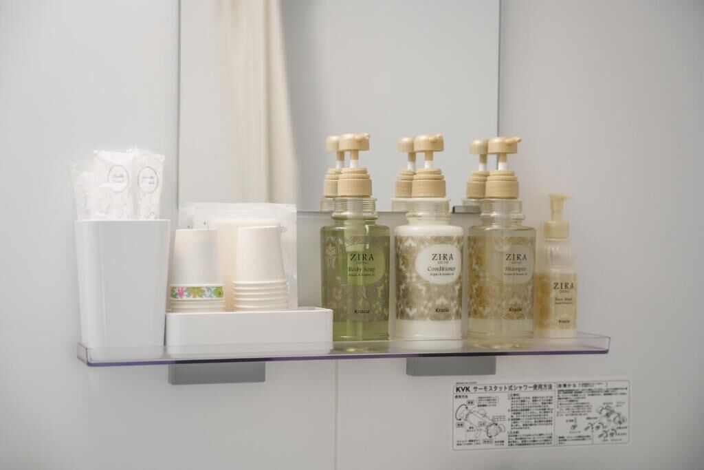 Uma prateleira no banheiro com diversos produtos ZIRA, incluindo sabonete líquido, condicionador e shampoo.