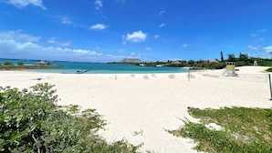 A beach with clear skies, a boat, and a distant cruise ship. - Lulu Manza (Onna)