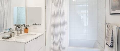 A modern bathroom with a white vanity, a bathtub, and a shower curtain.