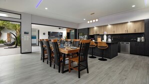 A modern kitchen with dark wood cabinets, a central island, and a dining area with a wooden table and chairs.