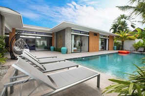 A modern house with a swimming pool, lounge chairs, and a hanging chair. - Stunning 4 bedrooms pool villa at Rawai (Tambon Rawai)