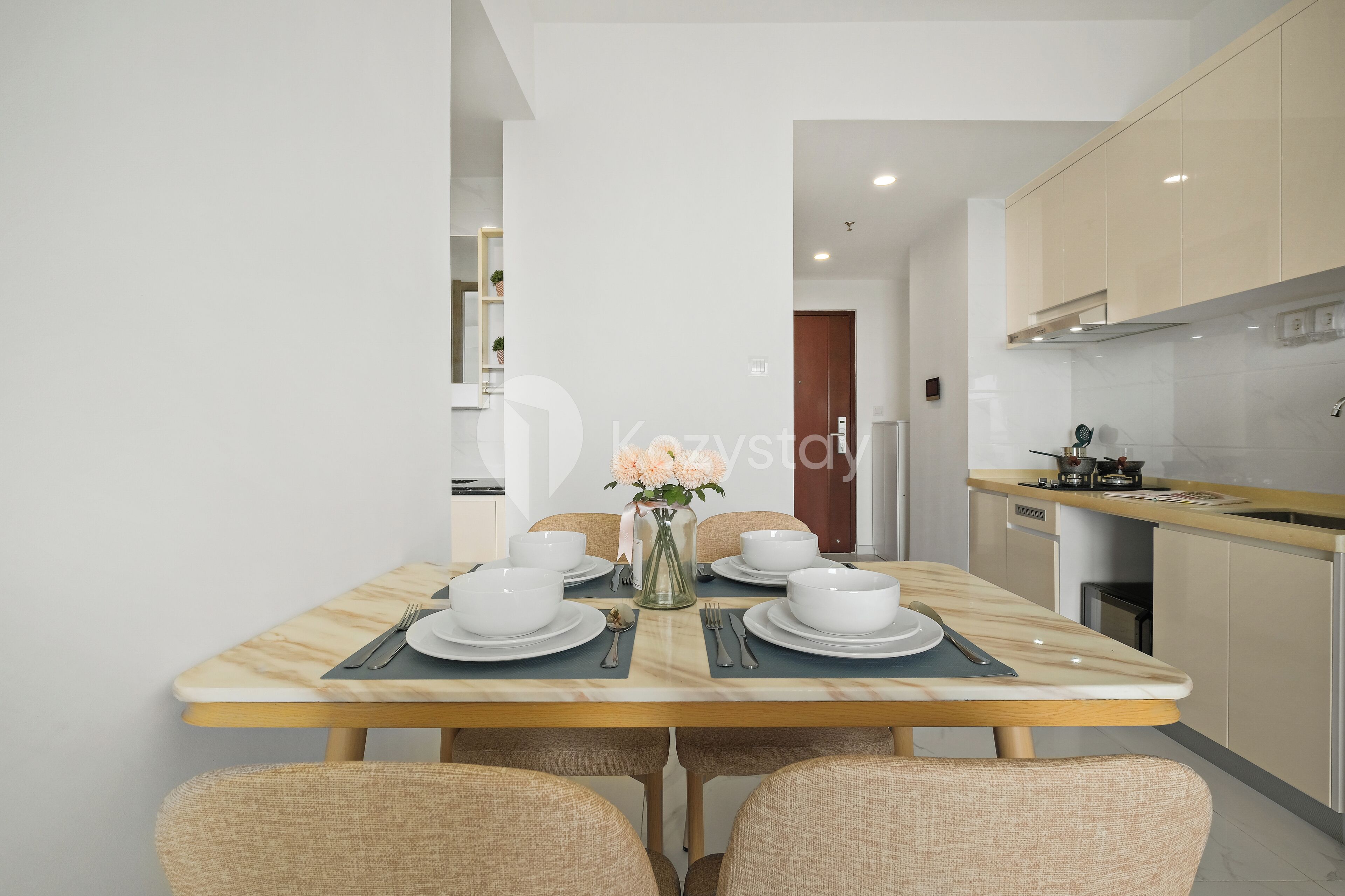A modern dining area with a marble table, four chairs, and a vase with flowers.