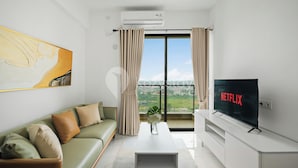 Een moderne woonkamer met een groene bank, een witte salontafel en een televisie waarop 'NETFLIX' staat.