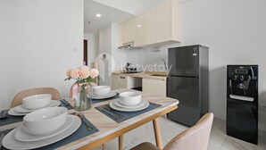 Een moderne keuken met een eettafel voor vier personen, een koelkast, een waterdispenser en een vaas met bloemen.