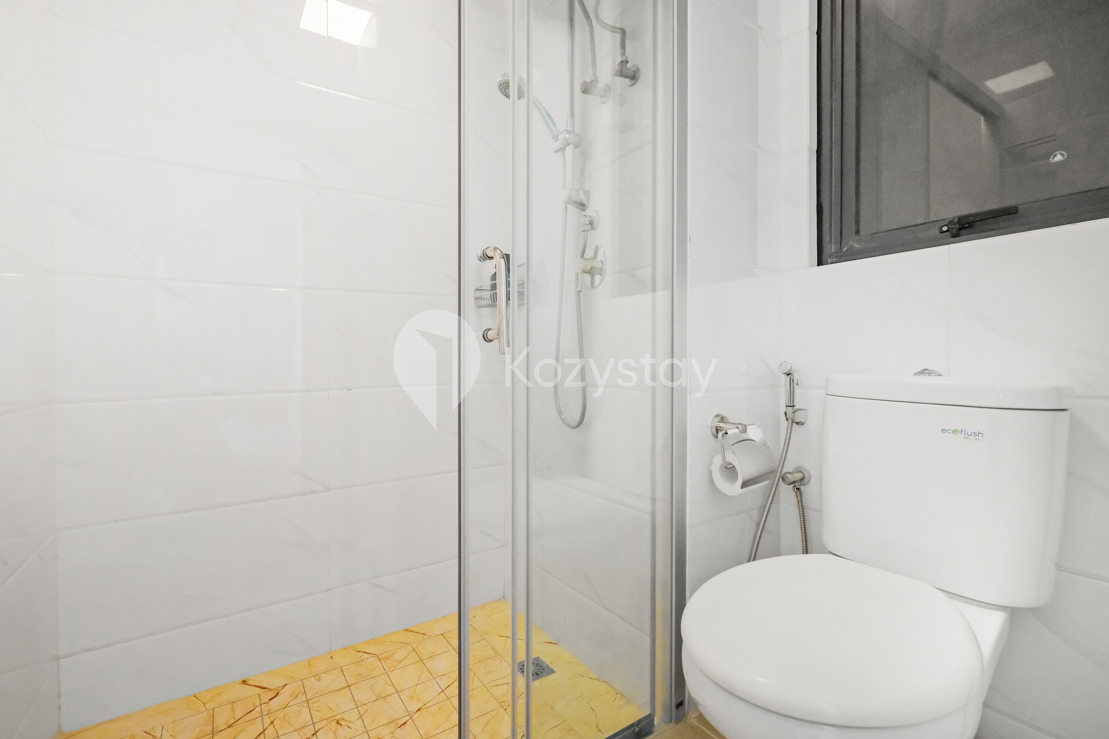 Un bagno moderno con box doccia in vetro, un water bianco e un tappetino da doccia giallo fantasia.