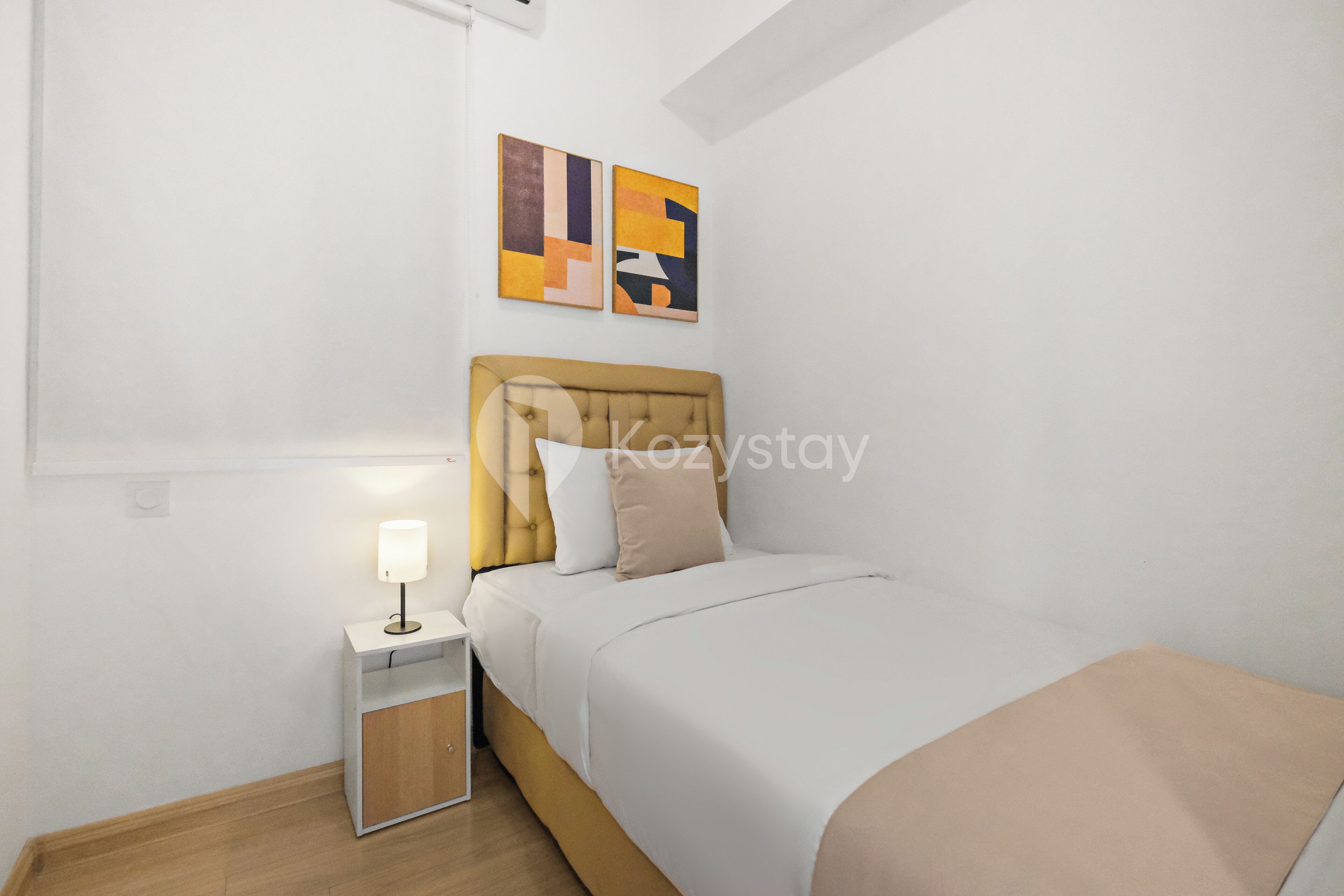A bedroom with a bed, nightstand, lamp, and abstract wall art.