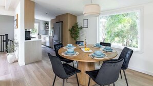 Une cuisine moderne dotée d’un îlot central, de chaises noires et d’une table à manger pouvant accueillir six personnes.