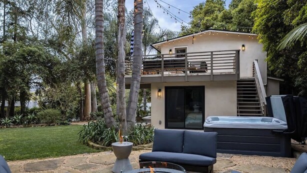 Une maison moderne dotée d’un foyer extérieur, d’un espace salon extérieur et d’un jacuzzi.