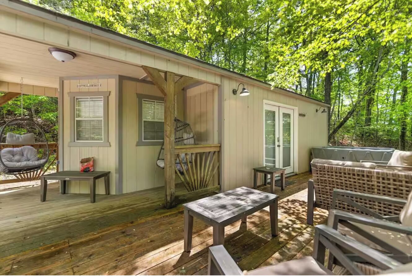 A wooden deck with outdoor seating, a covered porch, and a small table.
