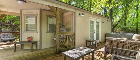A wooden deck with outdoor seating, a covered porch, and a small table.