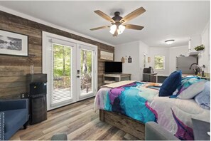 A bedroom with a bed, a ceiling fan, a TV, a desk, and a refrigerator. - Luxury Hilltop Couples Cabin with Hot Tub &  Red River Gorge Views (Stanton)
