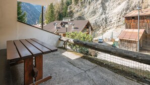 A wooden bench and a view of a mountain village with traditional buildings and a wooden structure. - Boiserie by Interhome (Campitello)