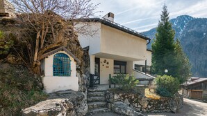 A rustic mountain house with a stone entrance, a small porch, and a view of the surrounding mountains. - Boiserie by Interhome (Campitello)