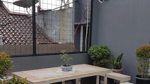 A patio with a rectangular table and benches, surrounded by potted plants. - Tebet Utara Residence (Jakarta)