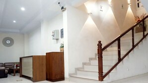 A modern interior with a staircase, a reception desk, and a living area. - Tebet Utara Residence (Jakarta)