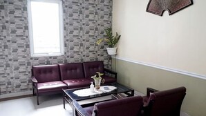 A room with a patterned wall, a window, a sofa, a coffee table, and a potted plant. - Tebet Utara Residence (Jakarta)