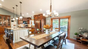 Una cocina amplia con armarios de madera, una isla central y un comedor con una mesa grande y sillas.