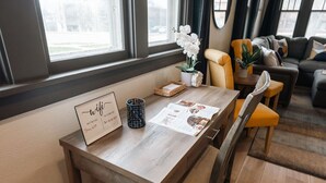 Ein Holztisch mit einer Tafel, auf der 'wifi' und 'Netzwerkpasswort' stehen, eine Zeitschrift, eine dekorative Tasse und ein Topf mit einer Orchidee.