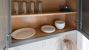 A kitchen cabinet with multiple shelves holding bowls, glasses, and plates.