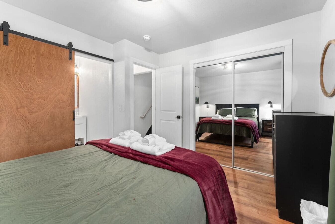 Una habitación de hotel con una cama, un armario, un espejo y un armario con puerta corredera.