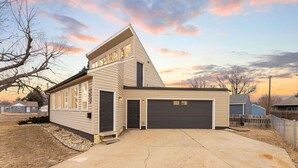 Een gelijkvloers huis met garage, oprit en een boom op de voorgrond.