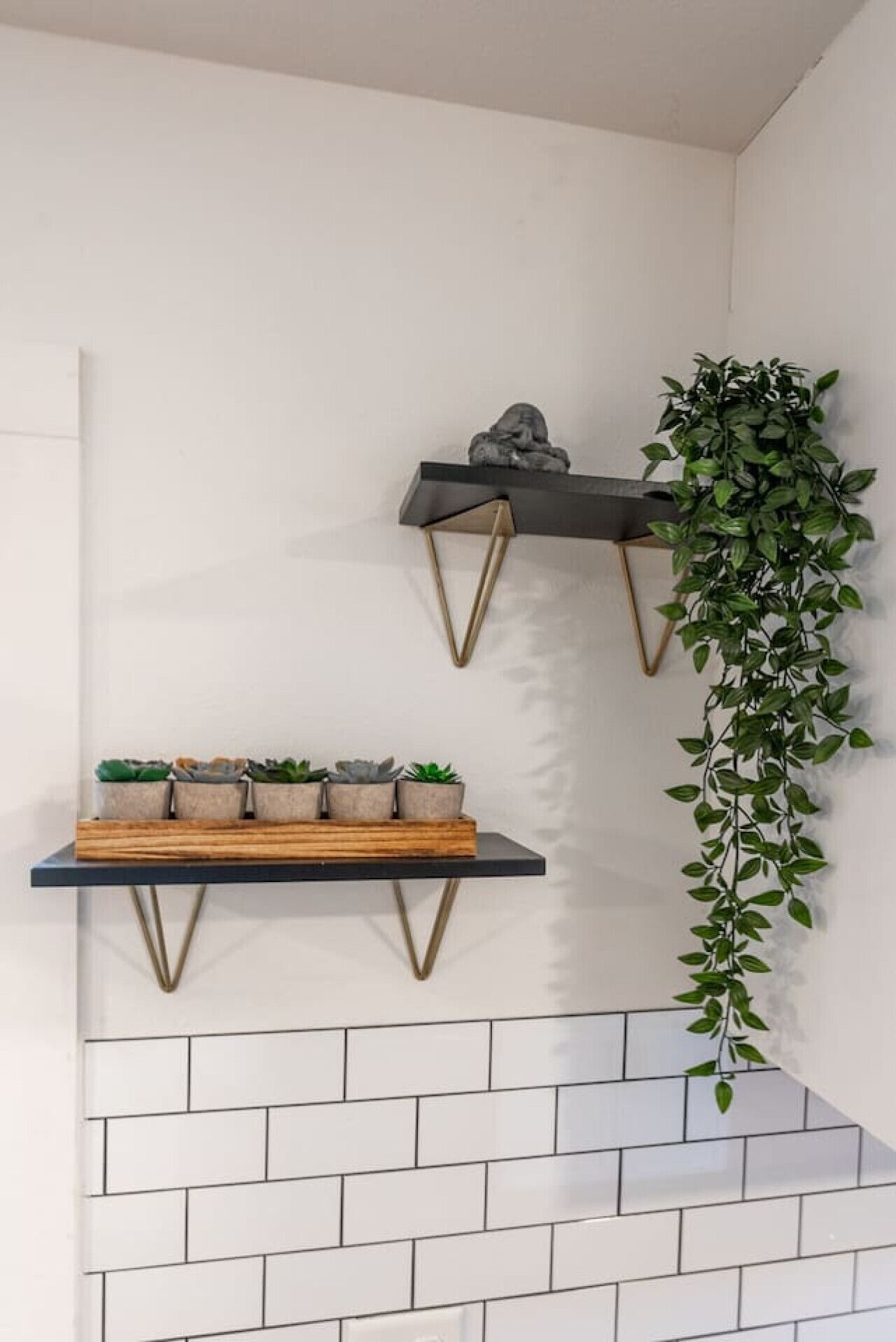 Ein modernes Interieur mit zwei Wandregalen, eines mit einer Pflanze und das andere mit Dekorationsobjekten.