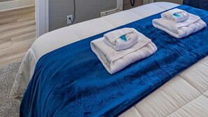 Ein Hotelzimmer mit Bett, einem flachbildfernseher an der Wand und einem blauen Vorhang.