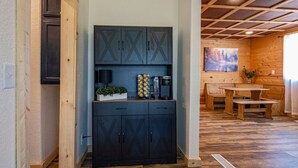 A modern kitchen with dark cabinets, a wooden bench, and a painting on the wall.