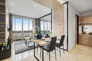 A modern living room with a dining area, large windows, and a kitchen. - Tensia by Kozystay - Taman Sari (Jakarta)