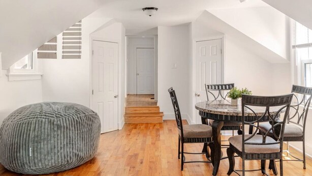 A dining area with a round table, four chairs, and a grey bean bag. A staircase leads to another room. - Cozy Apartment in Ypsi with Wi-Fi (Ypsilanti)