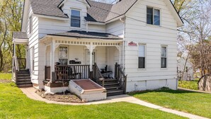 A two-story white house with a porch, a staircase, and a garage. - Cozy Apartment in Ypsi with Wi-Fi (Ypsilanti)
