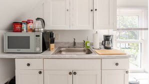 A kitchen with white cabinets, a microwave, a coffee maker, and a sink. - Cozy Apartment in Ypsi with Wi-Fi (Ypsilanti)