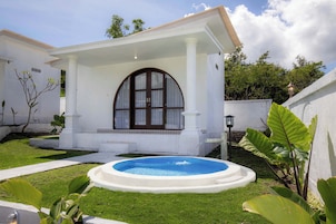 Un edificio blanco con un porche cubierto y una piscina.