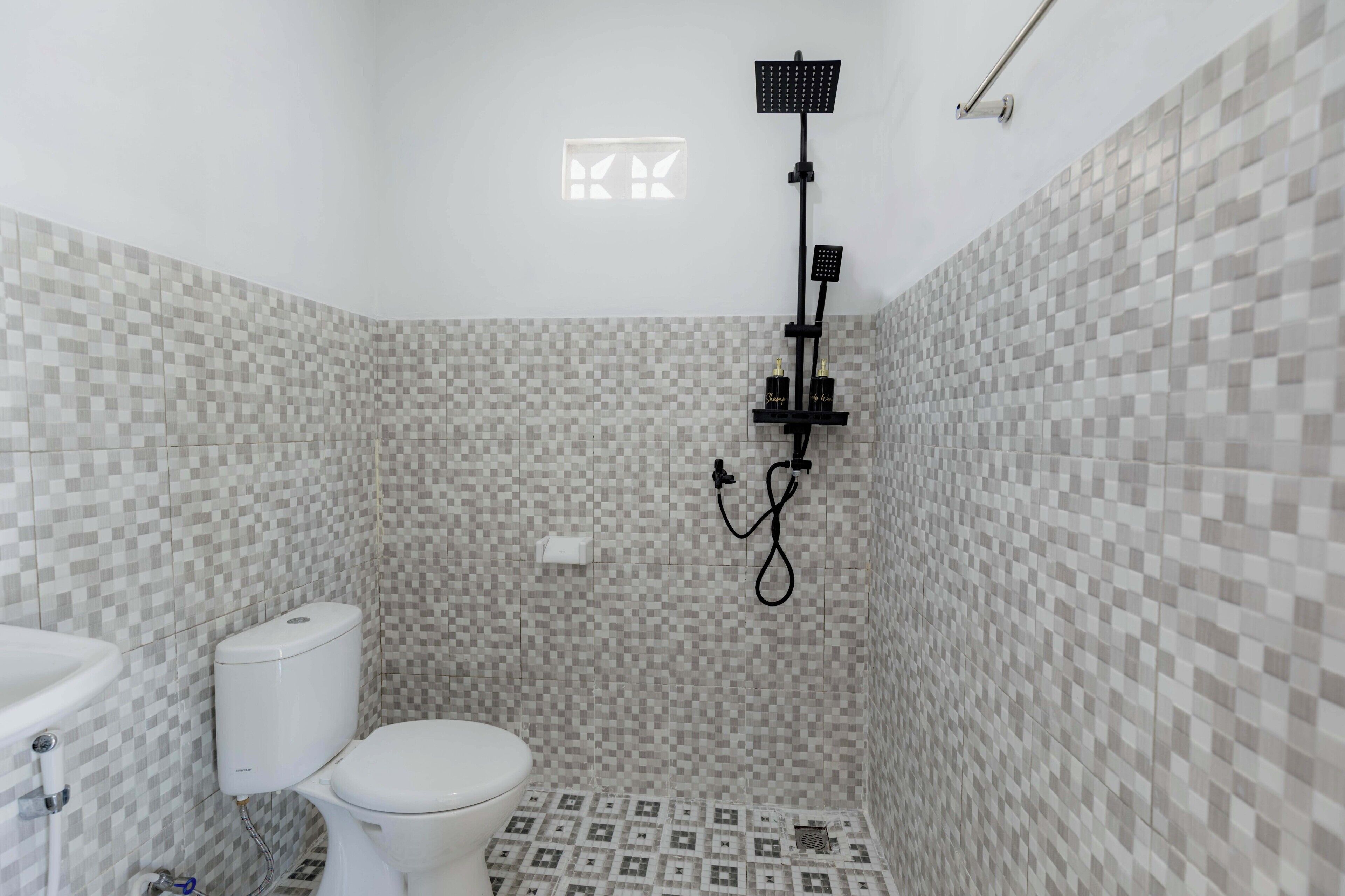 Een badkamer met toilet, douche en betegelde wanden.