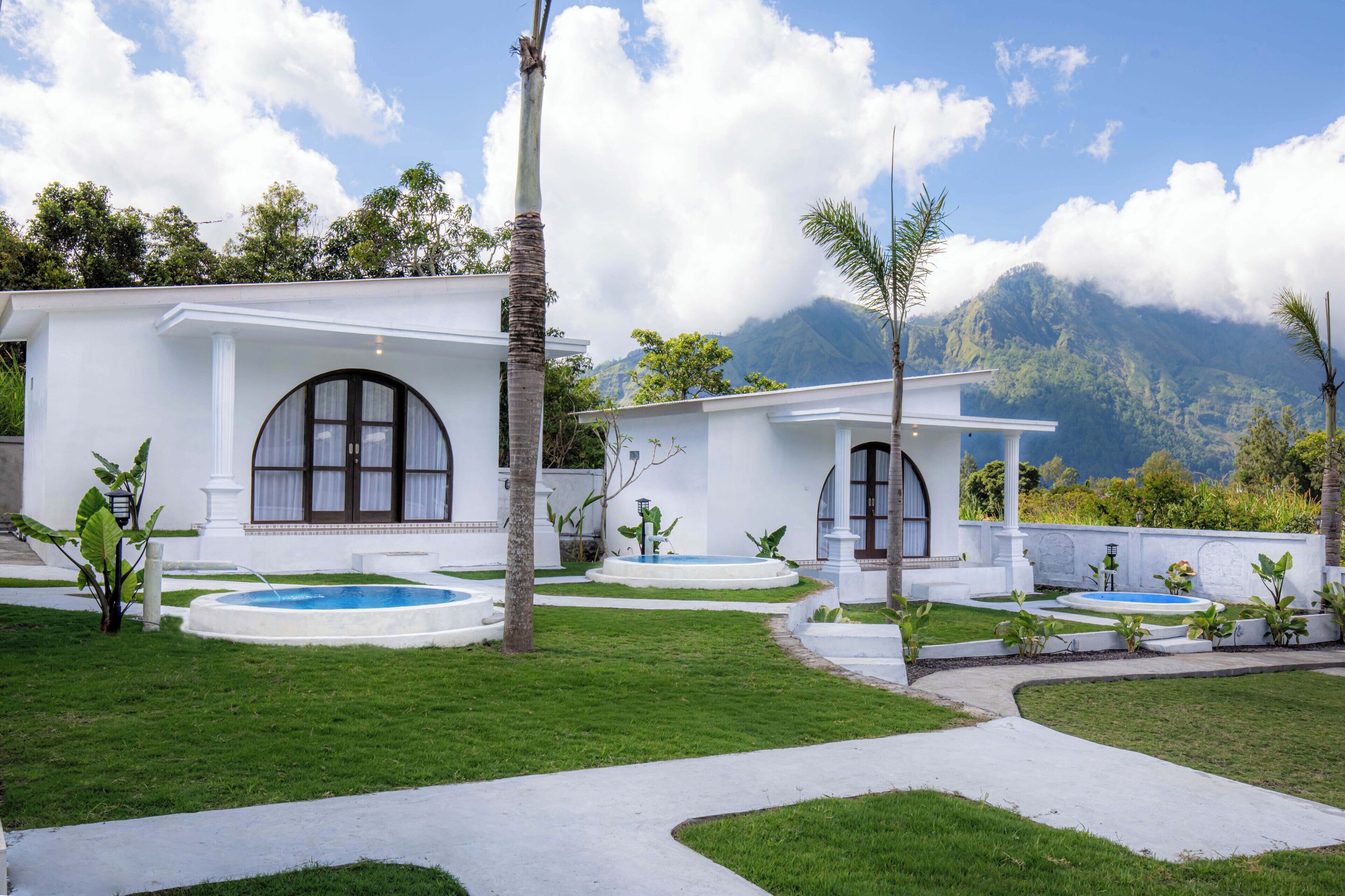 A white building with arched windows and a pool area.
