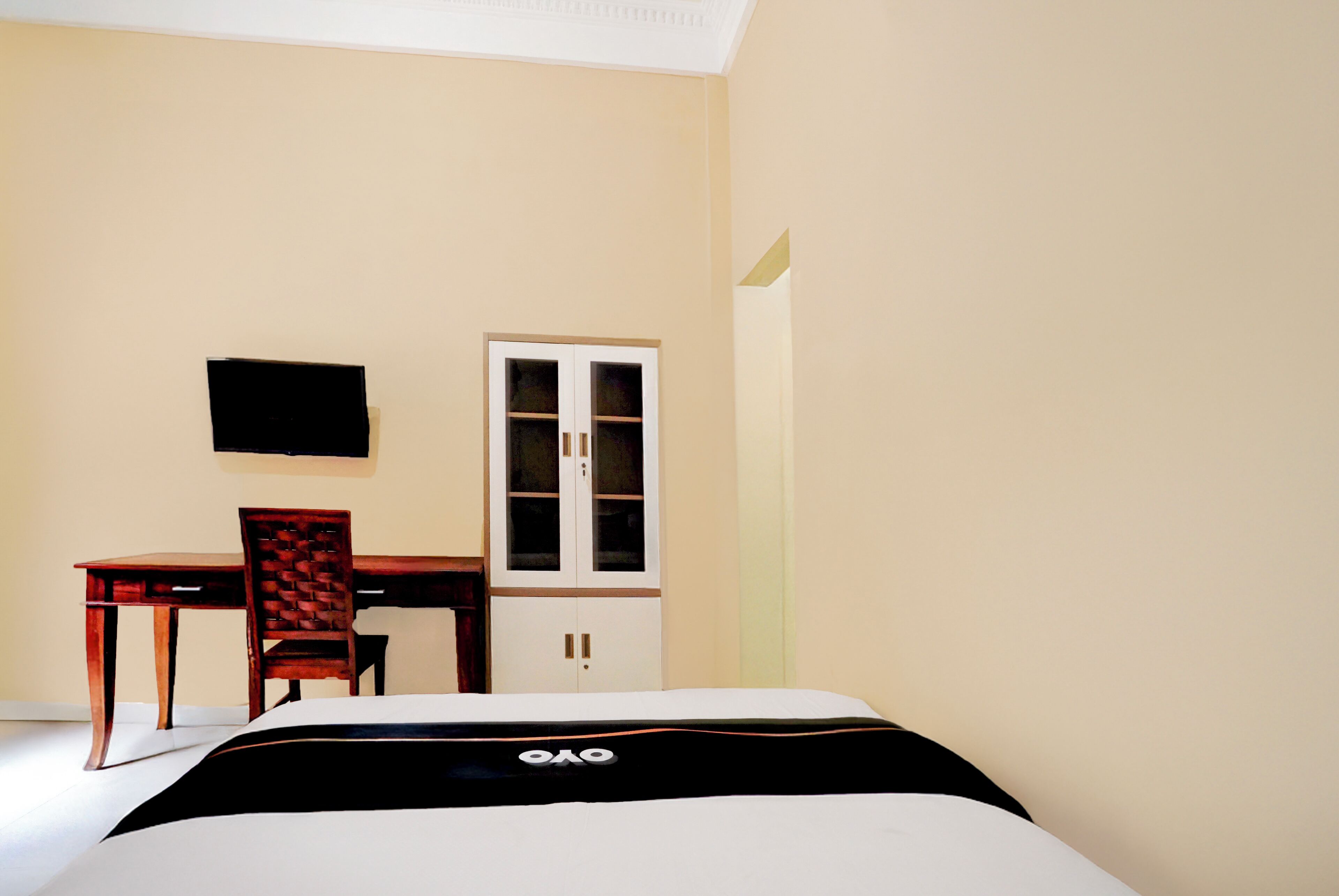 A hotel room with a bed, a desk, a chair, and a cabinet.