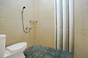 Ein Badezimmer mit Toilette, einer Dusche mit Glastür und gefliesten Wänden.