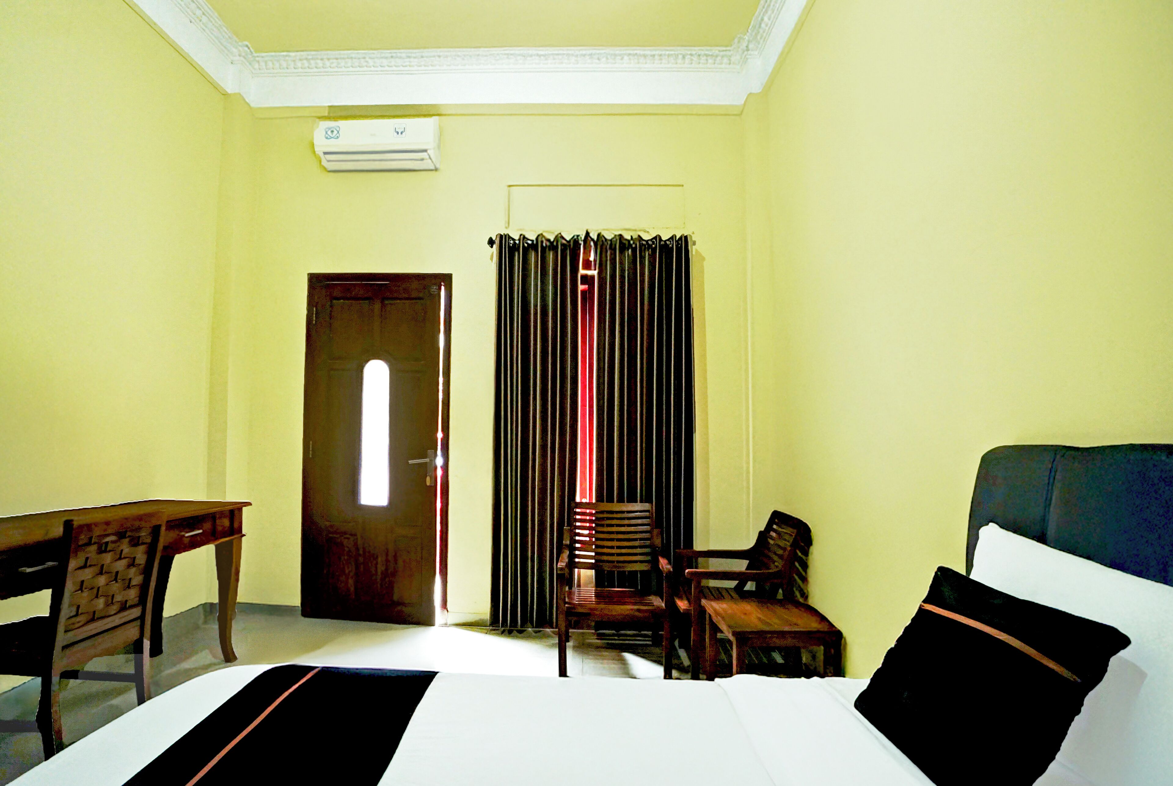 A room with a bed, a desk, a chair, and a window with curtains.