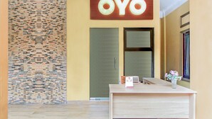 Un área de recepción con un mostrador de madera, una pared con diseño de mosaico y una puerta con la etiqueta "OYO".