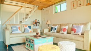 A living room with a staircase, a fan, a lamp, and a coffee table. - Pine Beach House (Alappuzha)